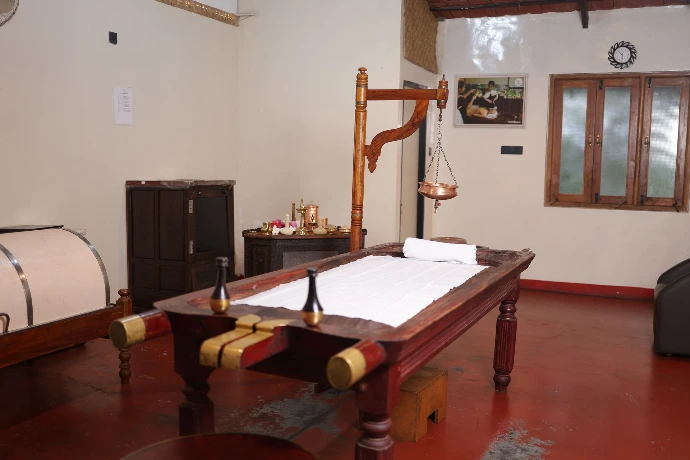 Traditional wooden Panchakarma droni massage table in a therapy room at Tapasya Health & Wellness