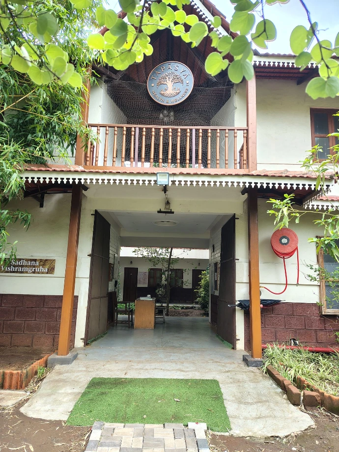 Traditional double-storey guest cottage with courtyard lawn at Tapasya Health & Wellness