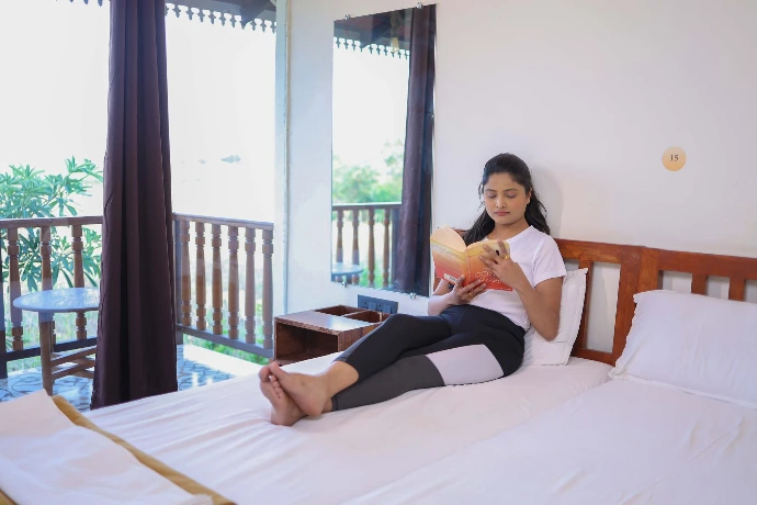 Individual relaxing on the bed in a private deluxe room at Tapasya Health & Wellness Ayurveda retreat