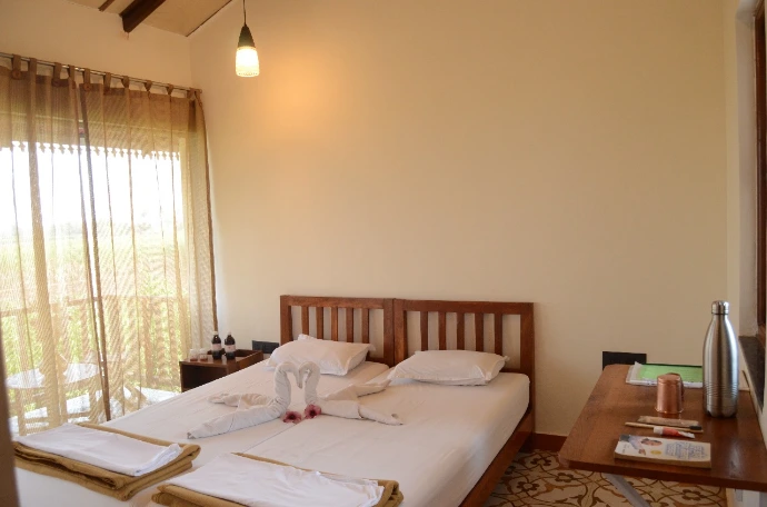 Neatly made twin beds in a bright, airy patient room at Tapasya Health & Wellness