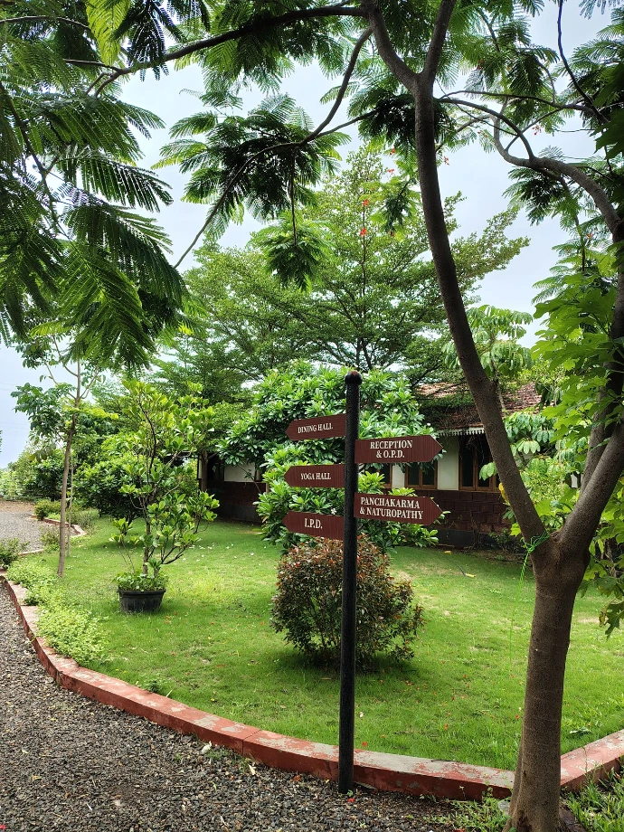 Landscaped lawn with plants and directional signage at Tapasya Health & Wellness campus