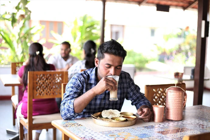 Individual enjoying a fresh Ayurvedic meal in the open-air garden dining area at Tapasya Health & Wellness