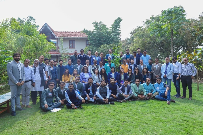 Group photo of corporate wellness retreat participants on the lawn at Tapasya Health & Wellness